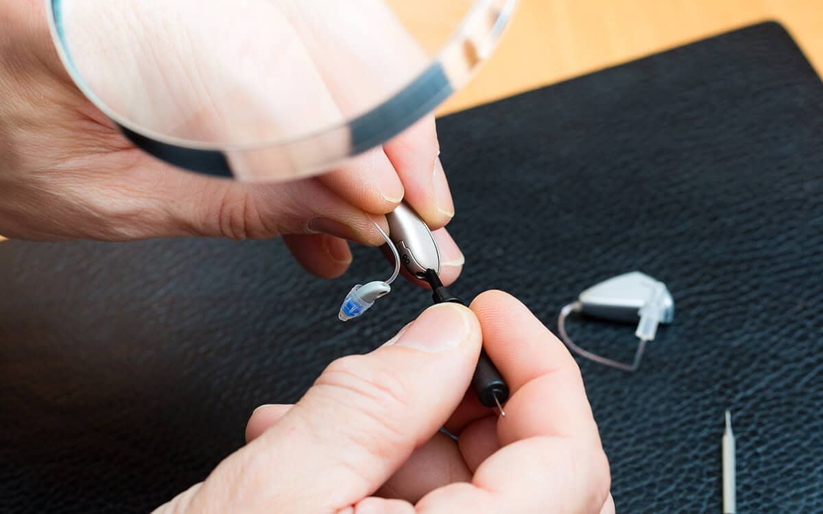 man fixing hearing aid